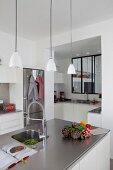 Bright, open-plan kitchen with stainless steel elements and internal windows above counter