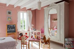 Pink walls, play table and antique wardrobe in vintage-style child's bedroom