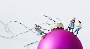 Miniature figurines of women stuck onto pink Christmas bauble