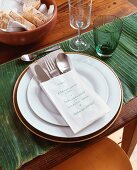 Place setting on banana leaf with menu written in paper cutlery bag