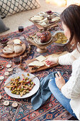 A picnic-style Christmas meal on a kilim rug with a cheese platter, salad and roast ham