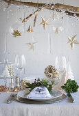 A table decorated for Christmas with paper decorations and a napkin ring of herbs