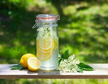 Homemade elderflower syrup with lemons on a table outside
