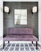 Gepolsterte Sitzbank mit violettem Wildlederbezug vor grau tapezierter Wand, oberhalb Wandspiegel zwischen Leuchten mit weißem Schirm