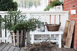Fir tree in wooden basket next to lantern on bench on veranda