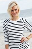 Blonde Frau in schwarz-weiss gestreiftem Langarmshirt am Strand