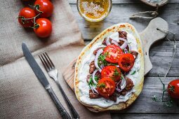 Pitta bread topped with beef, cream cheese, tomatoes and onions