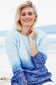 A blonde woman on a beach wearing a blue angora jumper