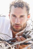 A young man wearing a white shirt holding brittle twigs