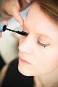 A young woman having mascara applied