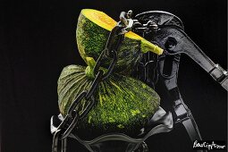 A green squash with a chain and a pair of pliers