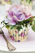 Seidenblumen und Efeu in bunter Cupcake-Manschette als Tischdeko