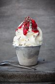 Frozen yoghurt in a metal cup with chia seeds and raspberry sauce