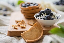 A shortcrust pastry dish with blueberries and a bowl of blueberries and hydrangea flowers