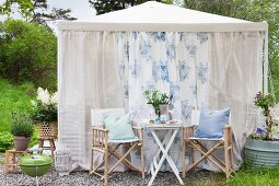 Table for two in front of romantic garden pavilion hung with airy fabric