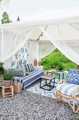 Lounge in möbliertem Gartenpavillon mit luftigem Stoffbezug auf gekiestem Platz