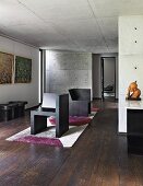Raum mit dunklem Holzboden, moderner Kunst und Sichtbeton an Wänden und Decke