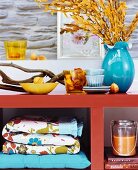 Autumn arrangement of twigs, branches and accessories on orange-painted shelves