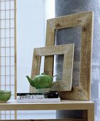 Oriental decoration ideas: simple wooden picture frames on a table leaning against a pillar