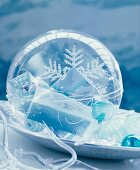 Plexiglas bauble filled with small wrapped gifts on decorative plate