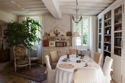 Oval dining table and loose-covered chairs in rustic, country-house dining room