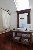 Dark wooden washstand below mirror and skylight next to wood-clad bathtub with shower curtain