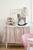 Rocking horse ornament and small cases on dressing table with floral skirt
