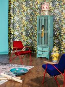 Retro armchairs, Chinese porcelain accessories and turquoise cupboard against patterned wallpaper