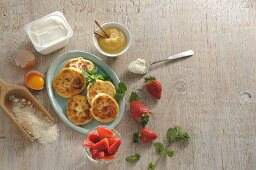 Sirniki (Russian quark pancakes) with apple sauce and strawberries