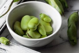 Fresh fava beans in a white bowl