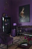 Room in shades of purple: armchair with mauve cover and antique bench below oil painting on wall painted aubergine