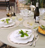 A festively laid garden table with bunches on herbs as napkin decorations