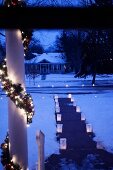 Front garden at twilight romantically decorated with candle lanterns made from paper bags and garlands with fairy lights