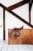 Saddle on wooden balustrade below wooden beams