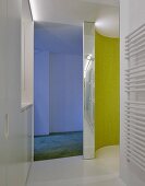 Gebogene gelbgrüne Mosaikfliesenwand im Designer-Duschbereich, im Hintergrund bläuliches Licht