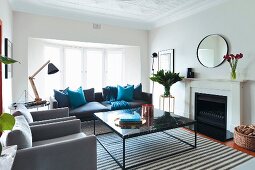 Elegant coffee table on striped rug and armchair and sofa in various shades of grey in traditional living room