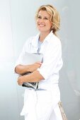 A blonde woman wearing a white shirt-blouse an holding books