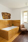 Mit ockerfarbenem Naturstein verkleidete Badewanne in elegantem Landhausbad