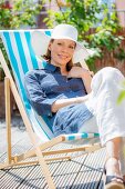 A woman wearing a sun hat sitting in a striped deckchair