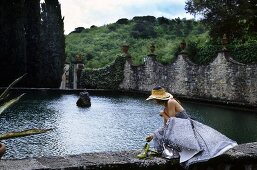 A young woman wearing an evening dress on a wall with water in the background