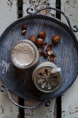 Vegan hazelnut milk in glasses with lids on a tray