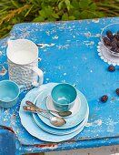 Gedeckter Tisch mit Kaffeegeschirr, Brombeeren und Milch im Garten