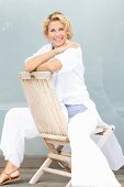 A blonde woman sitting backwards on a wooden chair