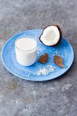 A glass of coconut milk, fresh coconut and grated coconut