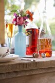 Bottle painted pale blue and used as vase for autumn flowers and drinks on rustic wooden table