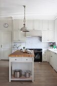 Free-standing island counter below metal pendant lamps in white, country-house kitchen