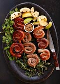 Sausage skewers with lemons on a bed of herbs