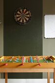 Table football table below darts board on green wall