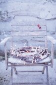 And ice decorative wreath with fairy lights on a snow-covered wooden chair