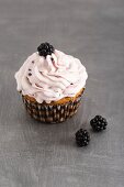 A cupcake with blackberries and blackberry cream